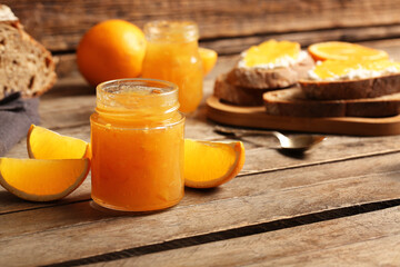 Naklejka premium Jar of sweet orange jam on wooden background