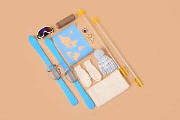 Composition with world map, skis, winter accessories and compasses on color background