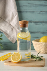 Bottle of fresh lemonade with rosemary on white wooden table
