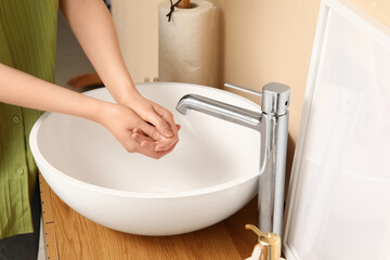 Woman washing hands in stylish bathroom