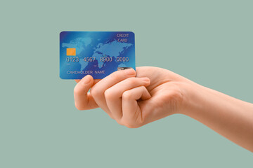 Female hand with credit card on light turquoise background, closeup