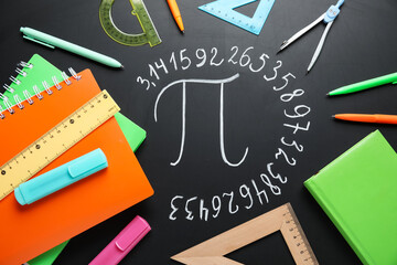 Number Pi written on black chalkboard with notebooks and stationery, top view