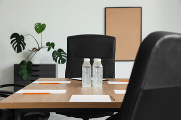 Table with bottles of water and paper sheets prepared for business meeting in conference hall