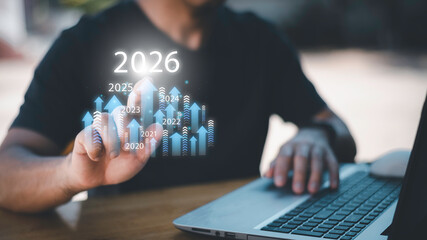 Businessman drawing digital growth arrows and bar graph with 2026 target. Futuristic concept for business goals, technology strategy, data-driven planning, success and innovation.