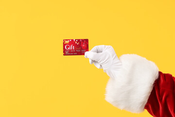 Santa Claus holding gift card on color background, closeup
