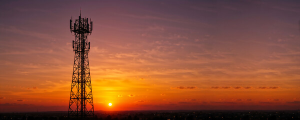 Silhouette of telecommunications tower against vibrant sunset sky. 5G and 6G mobile network antenna infrastructure. Copy space