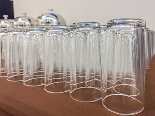 Row of clean upside down glass cups on brown table