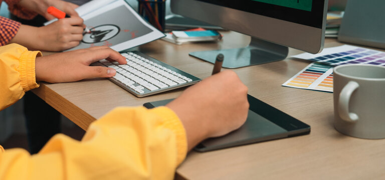 A vibrant creative workspace featuring a person using a digital drawing tablet next to a computer monitor, surrounded by color swatches and office supplies for inspiration. SACTR