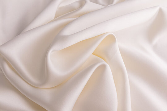 Elegant soft waves of satin fabric in cream, champagne. exquisite delicate material, texture. wedding concept. Festive background. layout for design.