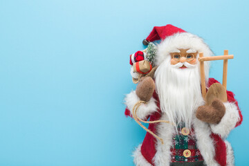 Santa Claus toy at light blue wall background. Pastel color. Closeup. Christmas decoration. Empty place for text. Front view.