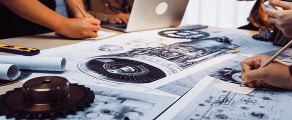 A group collaborates in a vibrant workspace, surrounded by engineering blueprints and technical drawings, highlighting creativity and teamwork in project planning. SACTR