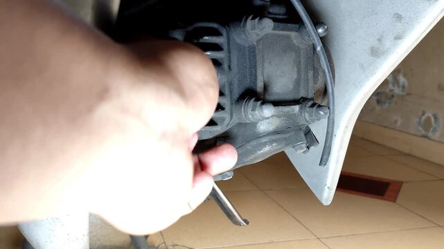 Close-up of a hand using a wrench to remove a motorcycle spark plug from the engine. Concept of mechanical repair, vehicle maintenance, garage service, and automotive care.