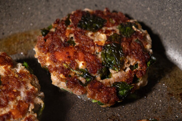 Cooking turkey meatballs with spinach in pan