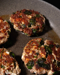 Cooking turkey meatballs with spinach in pan