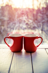 heart shaped mugs with tea on the background of a window in winter
