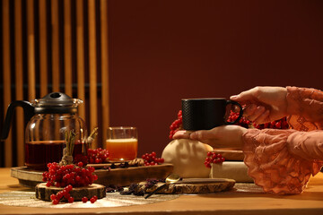 Young woman holding cup of hot viburnum tea at home