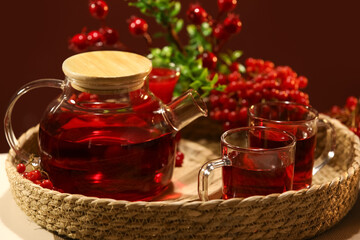 Tray with teapot and cups of tasty viburnum tea on table in living room, closeup