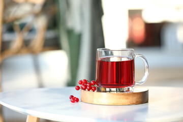 Cup of hot viburnum tea on table in living room, closeup