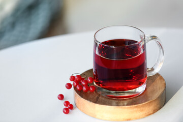 Cup of hot viburnum tea on table in living room, closeup