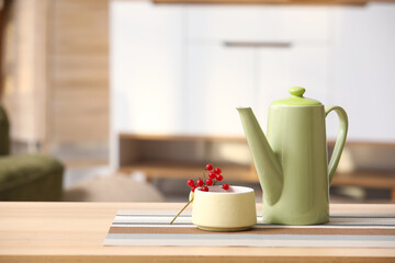Teapot and cup of hot viburnum tea on table in living room