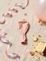 Neutral minimalist flat lay after birthday celebration featuring pastel confetti, deflated balloon, curled ribbons, cake crumbs and beige linen background for serene aesthetic