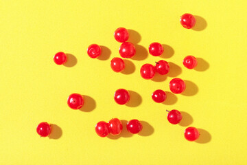 Scattered fresh viburnum berries on yellow background, closeup