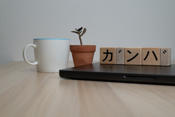 Wooden Blocks Spelling 'Kanba' on Laptop with Office Supplies