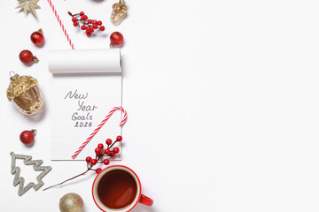Obraz premium Notebook with text NEW YEAR GOALS 2026, Christmas decor and cup of tea on white background