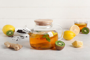 Teapot with tasty fruit tea and ingredients on white grunge table