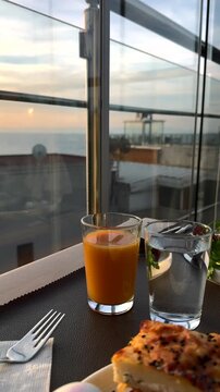 Orange juice and a glass of water are on the table.
A hearty breakfast with a view of the sunrise.
An early breakfast with a beautiful sunrise.
Fresh orange juice in a glass and a glass of cool water.