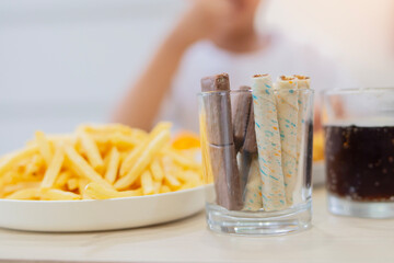 Colorful wafer stick rolls, chocolate in a glass with some snack and dark sparkling sofa