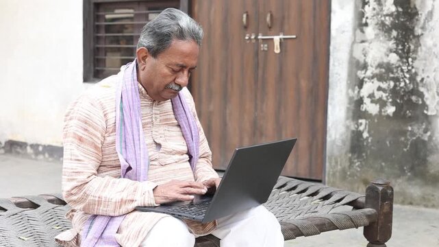 Senior rural indian man using laptop at home Check government scheme online on fast internet. Digital india concept. Wireless Technology. Asian elderly male learn computer