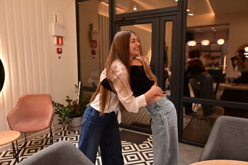 Warm hug between two female friends meeting at a café