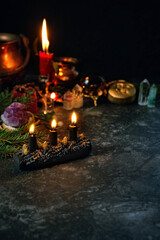 Wiccan altar for Yule holiday. Burning Yule log shape candle, amulets, minerals, witch cauldron, fir branches on dark table. Magic esoteric Ritual. witchcraft, ceremony for Yule, Winter Solstice