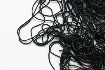 A cluster of thin black cords lies in a loose, chaotic tangle against a clean white background