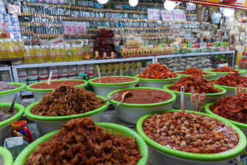 Hue market stall featuring basins of pickled seafood, fermented pastes, and eggplants against a background of bottled cajuput oil.