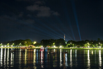 Dramatic green spotlights fan out over the Perfume River at night, illuminating boats and reflecting on the dark water surface.