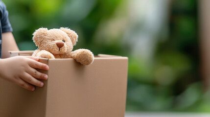 Child giving toy to charity box "donation", emotional scene, copy space