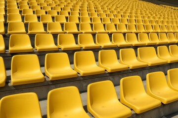 Rows of empty yellow plastic stadium seats arranged in a repetitive pattern on concrete steps under daylight, symbolizing anticipation and sport atmosphere. Ai generative