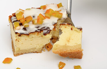 A piece of delicious cheesecake baked with a frosting of icing and candied orange peel