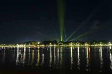Dramatic green spotlights fan out over the Perfume River at night, illuminating boats and reflecting on the dark water surface.