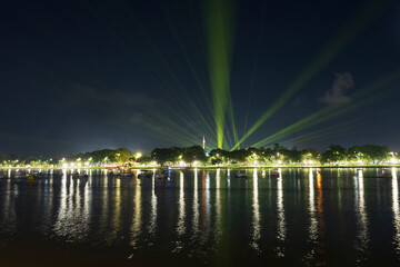 Dramatic green spotlights fan out over the Perfume River at night, illuminating boats and reflecting on the dark water surface.