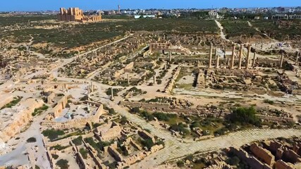Aerial drone view of Sabratha, an ancient Roman city in Libya, showing a vast archaeological site featuring temples, columns, and stone ruins that extend toward the sea