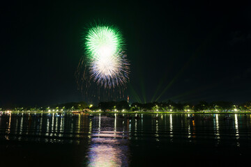 Spectacular gold fireworks exploding over the Perfume River in Hue, reflecting on the dark water amidst boats and green lasers.