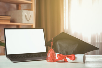 Diploma, graduation cap and laptop on white wooden table indoors, closeup