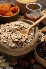 Making granola. Oat flakes, dried fruits and other ingredients on wooden table, closeup