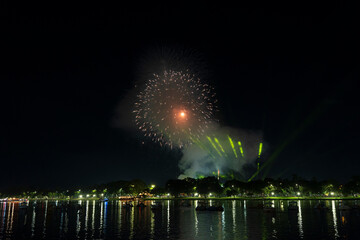 Dramatic green spotlights fan out over the Perfume River at night, illuminating boats and reflecting on the dark water surface.