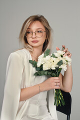 Portrait of a girl in a white suit holding flowers. Female portrait.	
