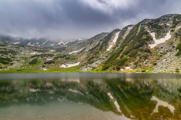Beautiful fir tree forests, pristine glacier lake, rocks and spring flowers in the Transylvanian Alps in summer