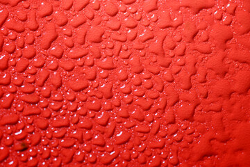 Closeup view of white fluid drops on a textured red background